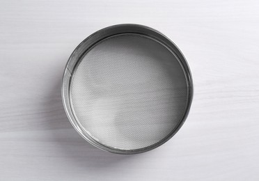 Photo of One metal sieve on white wooden table, top view