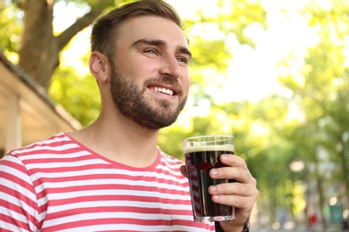 Photo of Handsome man with cold kvass outdoors. Traditional Russian summer drink