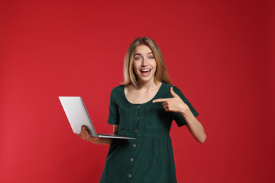 Photo of Portrait of emotional woman with modern laptop on red background