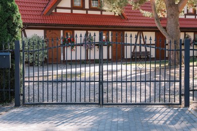 Photo of Closed metal gates near beautiful house on sunny day