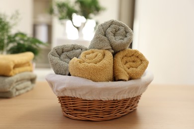Photo of Basket with towels on wooden table indoors. Spa time