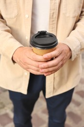 Photo of Coffee to go. Man with paper cup of drink outdoors, closeup