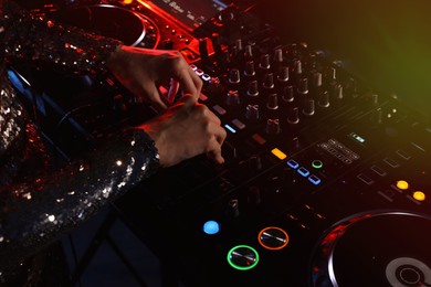 Photo of DJ creating music on modern console mixer in night club, closeup