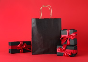Gift boxes and shopping bag on red background. Black Friday sale