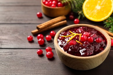 Photo of Cranberry sauce with orange peel on wooden table, space for text