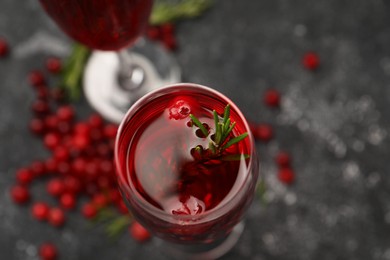 Photo of Tasty cranberry cocktail with rosemary in glass on gray table, above view