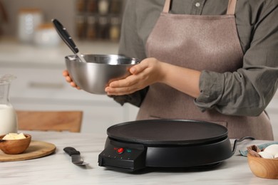 Woman cooking delicious crepes in kitchen, closeup