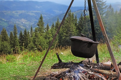 Photo of Cooking breakfast on fire in mountains. Camping season