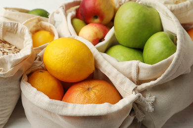 Photo of Cotton eco bags with fruits, closeup view