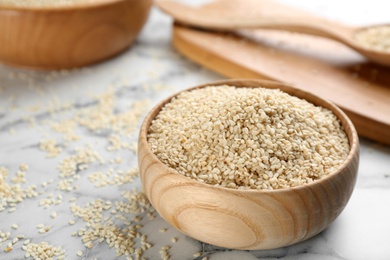Photo of Sesame seeds in bowl on white marble table