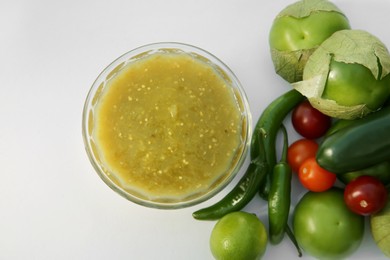 Photo of Bowl with delicious salsa sauce and ingredients on white background, flat lay