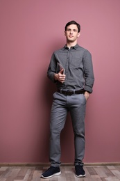Photo of Portrait of confident young man with tablet on color wall background