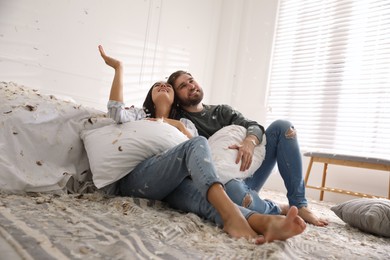 Photo of Happy young couple resting after fun pillow fight in bedroom