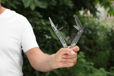 Photo of Man holding compact portable multitool outdoors, closeup