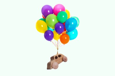 Image of Many balloons tied to wooden toy car flying on white background