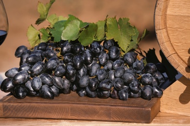 Photo of Wooden board with ripe wine grapes on table