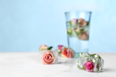 Photo of Composition with floral ice cubes on table against color background, space for text