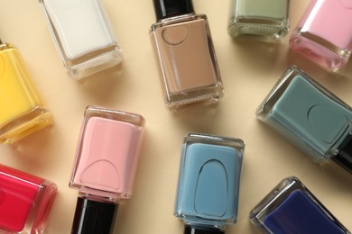 Colorful nail polishes in bottles on beige background, flat lay