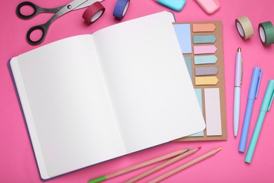 Open planner and stationery on pink background, flat lay. Space for text