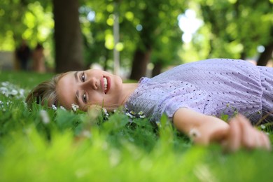 Photo of Beautiful woman lying on green grass in park. Spring sunny day