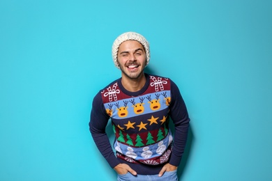 Photo of Young man in Christmas sweater and knitted hat on color background