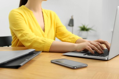 Photo of Home workplace. Woman working on laptop at wooden desk indoors, closeup