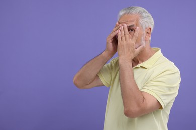 Photo of Embarrassed senior man covering face on purple background. Space for text