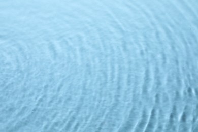 Photo of Rippled surface of clear water on light blue background, top view