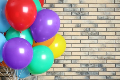 Photo of Bunch of bright balloons and space for text against brick wall