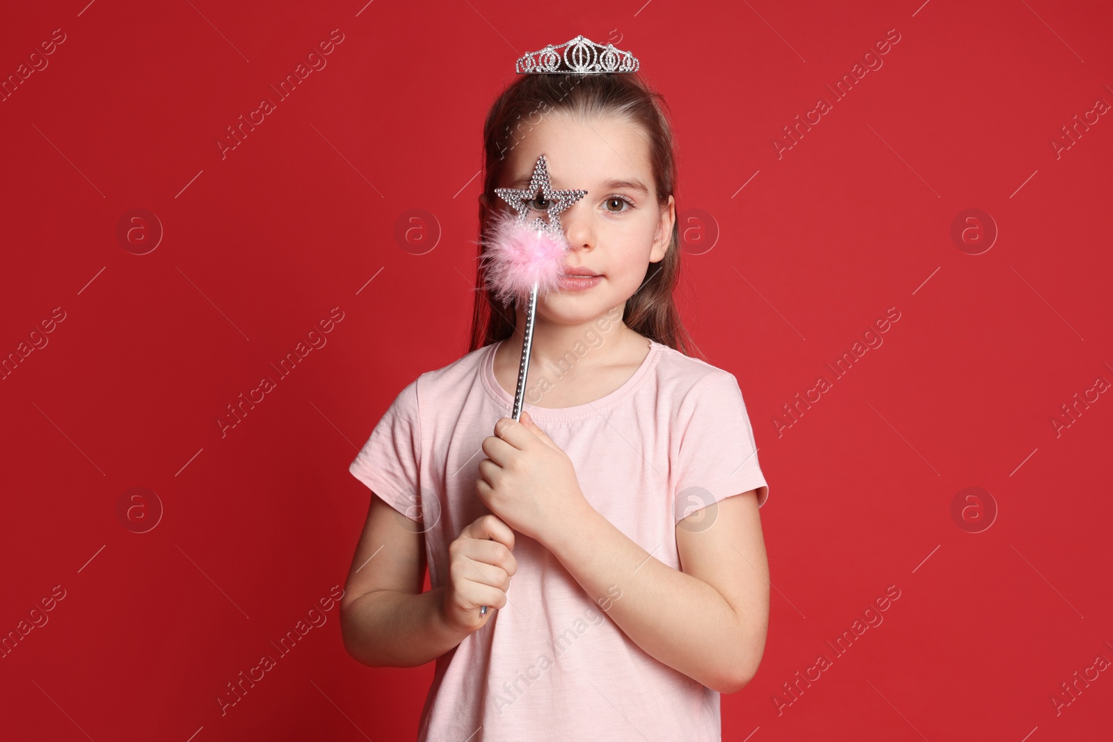 Photo of Cute girl in diadem with magic wand on red background. Little princess