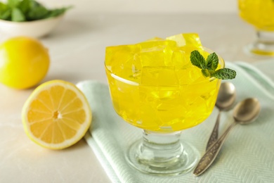 Photo of Glass bowl with tasty jelly cubes served on table, closeup