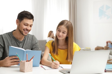 Photo of Father helping his teenager daughter with homework indoors