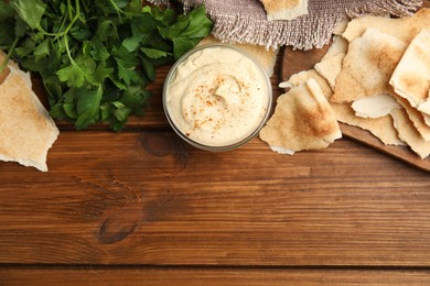 Delicious hummus with pita chips on wooden table, flat lay. Space for text
