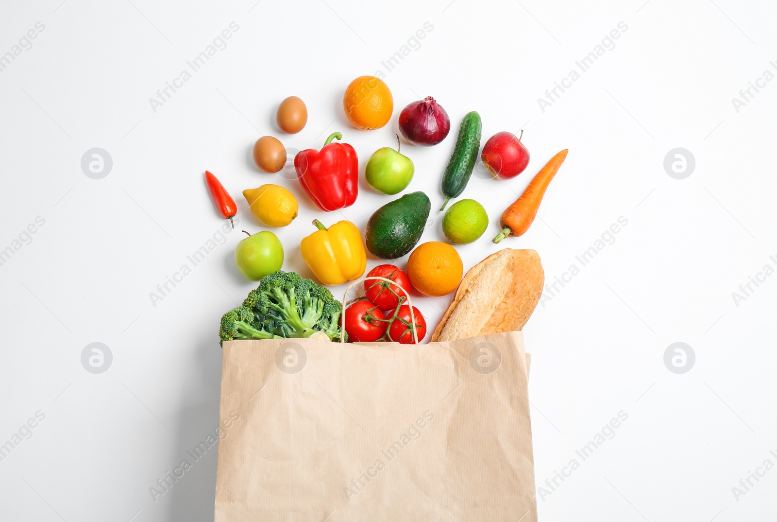 Photo of Paper bag with different groceries on white background, top view