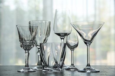 Photo of Different elegant empty glasses on grey table indoors