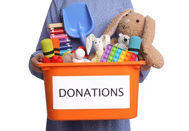 Photo of Woman holding donation box full of different toys on white background, closeup