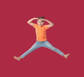Image of Happy cute girl jumping on red background