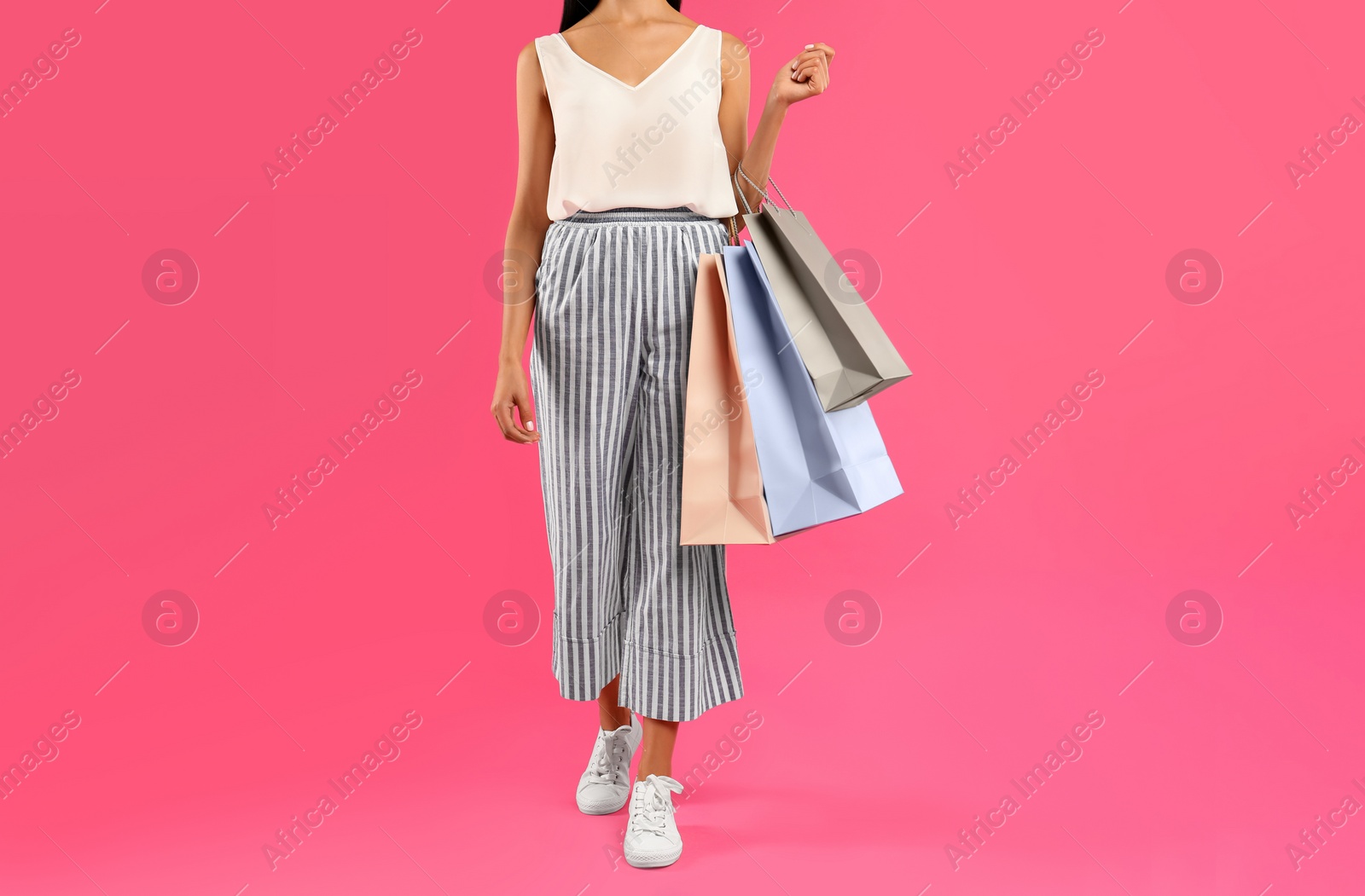 Photo of Young woman with paper shopping bags on pink background, closeup