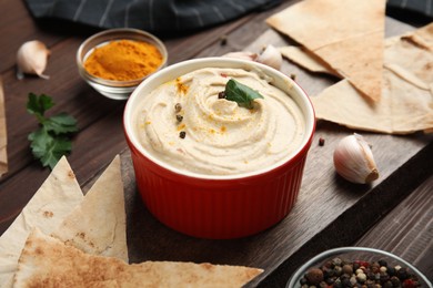 Photo of Delicious hummus with pita chips on wooden table, closeup