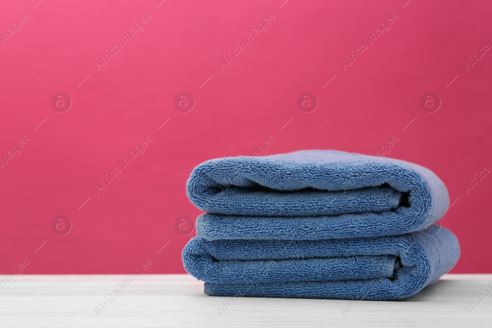 Photo of Soft clean towels on table against color background. Space for text