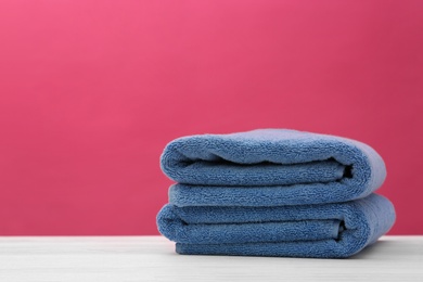 Photo of Soft clean towels on table against color background. Space for text