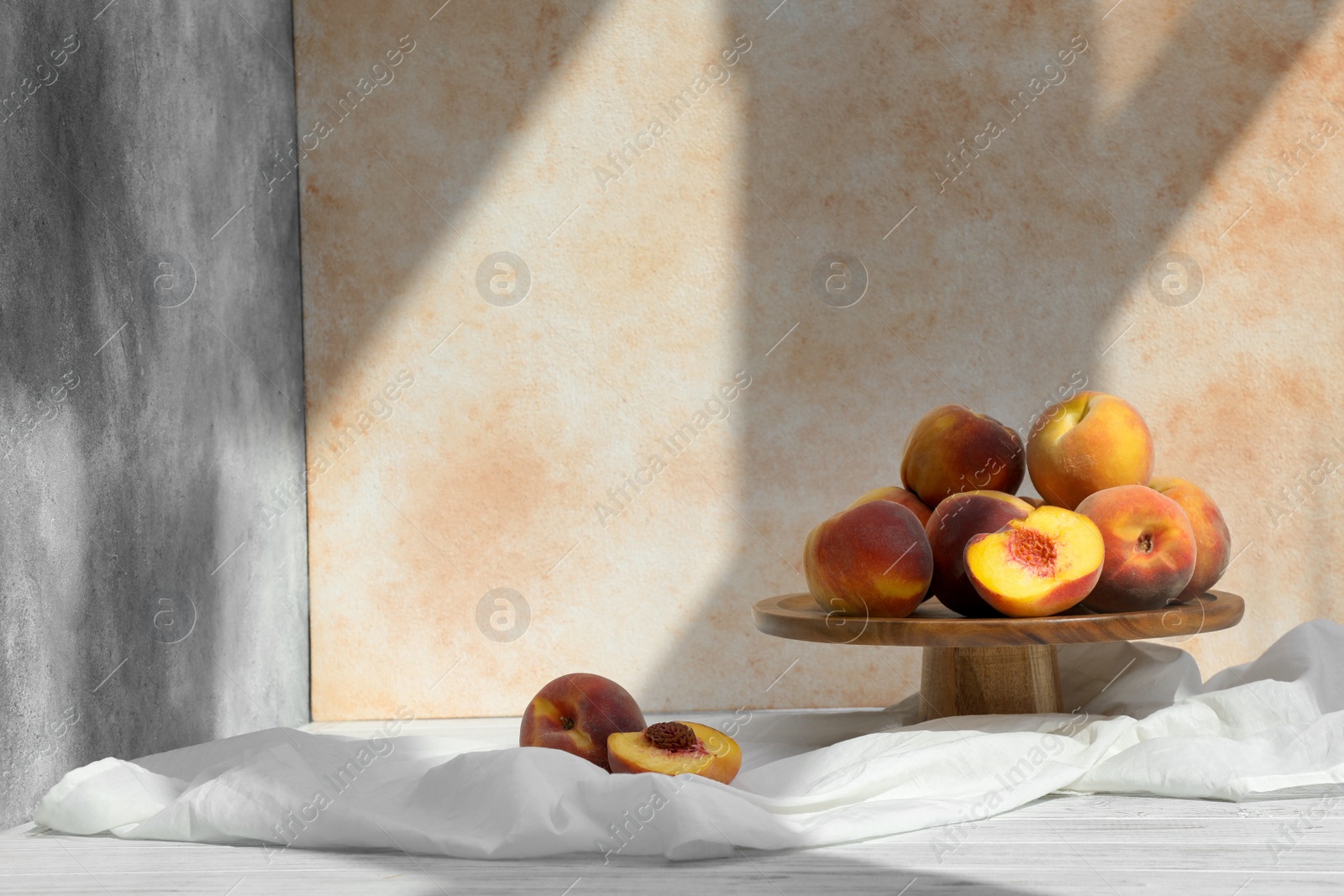 Photo of Stand with juicy peaches and double-sided backdrops in photo studio