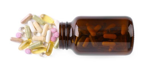 Bottle and different vitamin pills isolated on white, top view