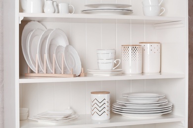 Stylish storage stand with different ceramic dishware at home