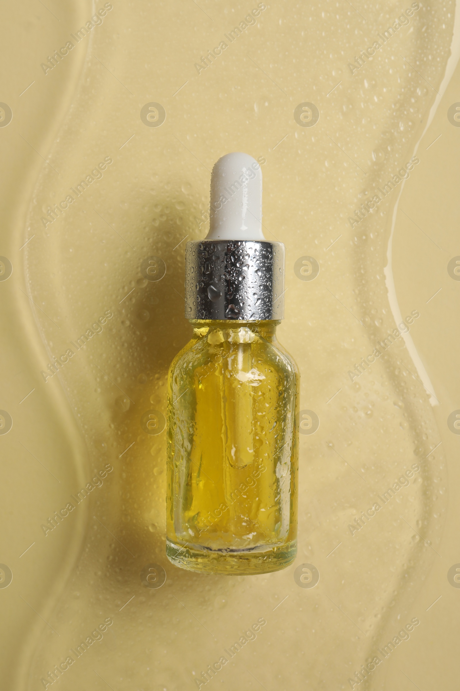 Photo of Bottle of cosmetic serum on beige background, top view