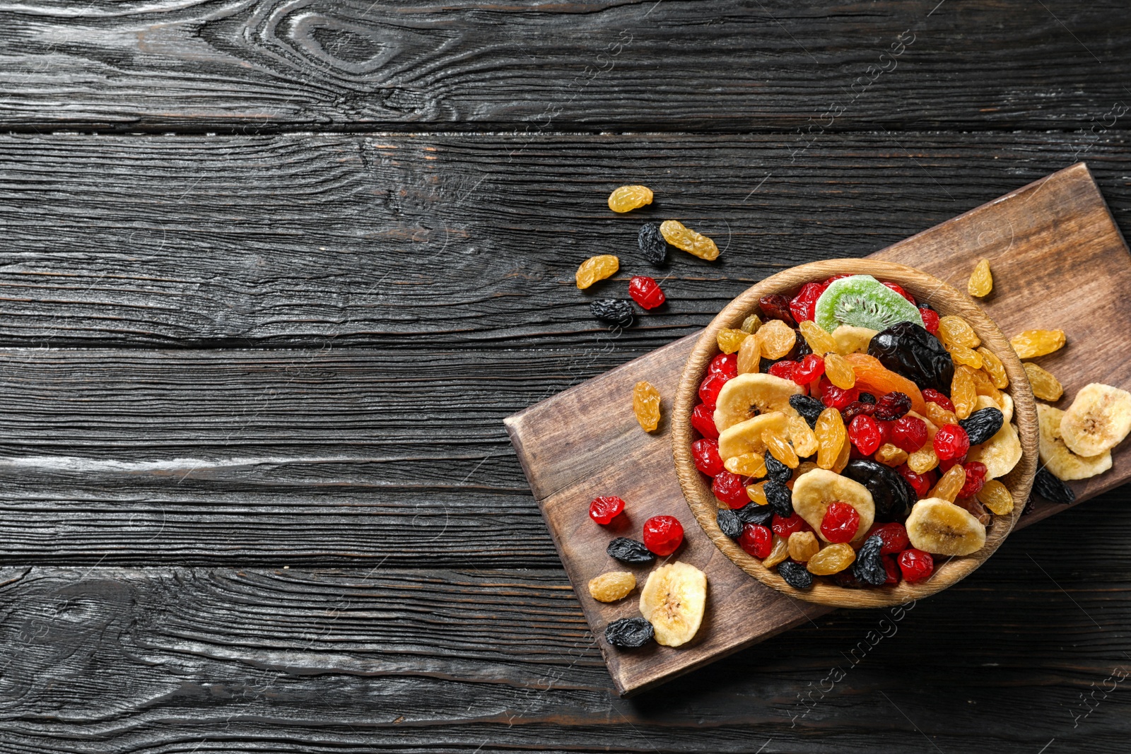 Photo of Bowl of different dried fruits on wooden background, top view with space for text. Healthy lifestyle