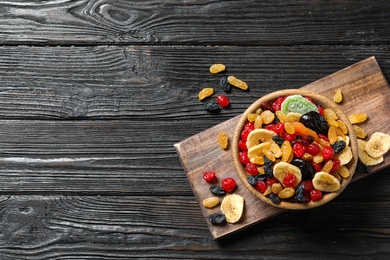 Bowl of different dried fruits on wooden background, top view with space for text. Healthy lifestyle