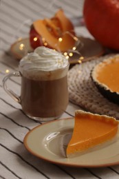 Fresh homemade pumpkin pie and cup of cocoa with whipped cream on table