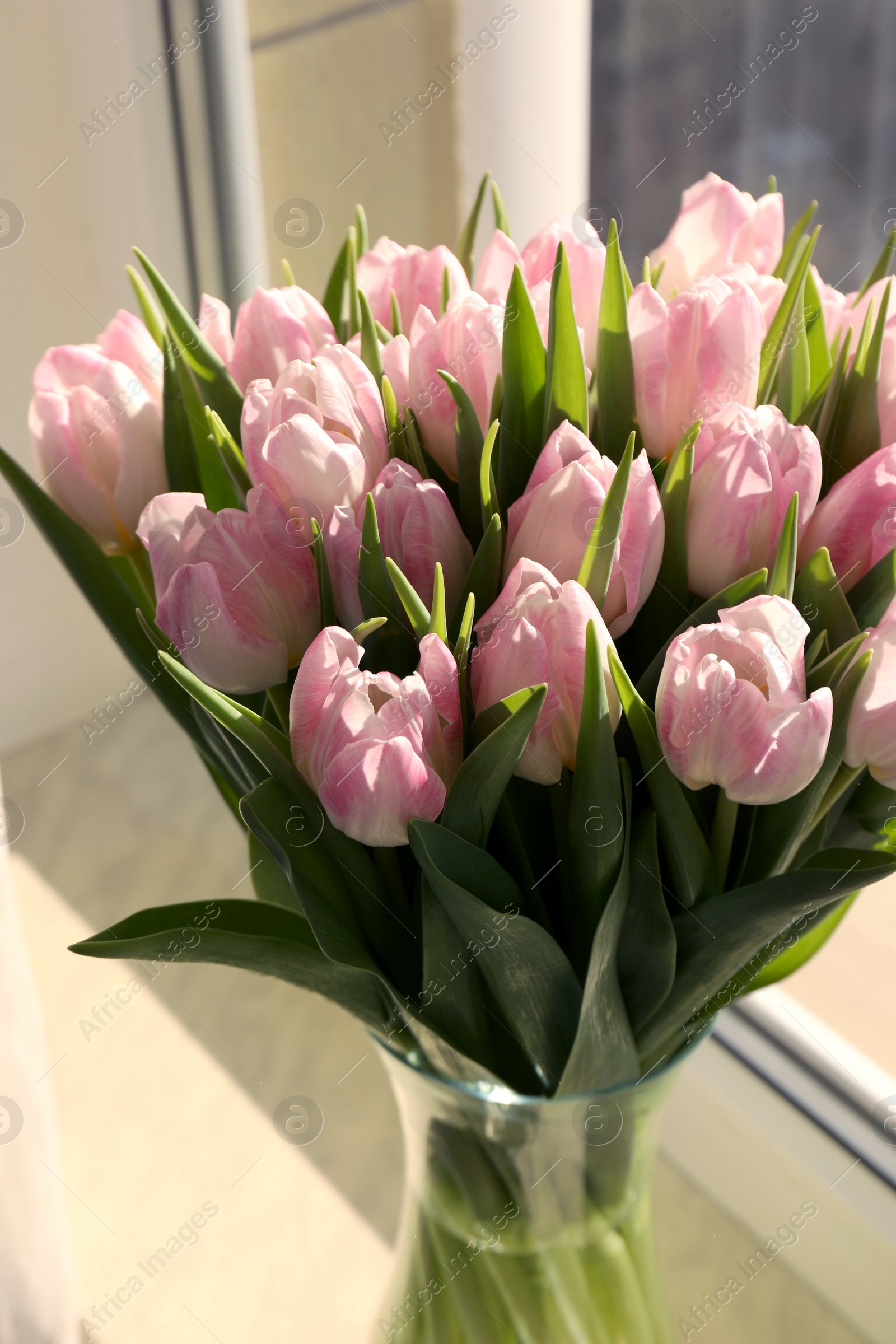 Photo of Spring is coming. Bouquet of beautiful tulip flowers in glass vase on windowsill indoors