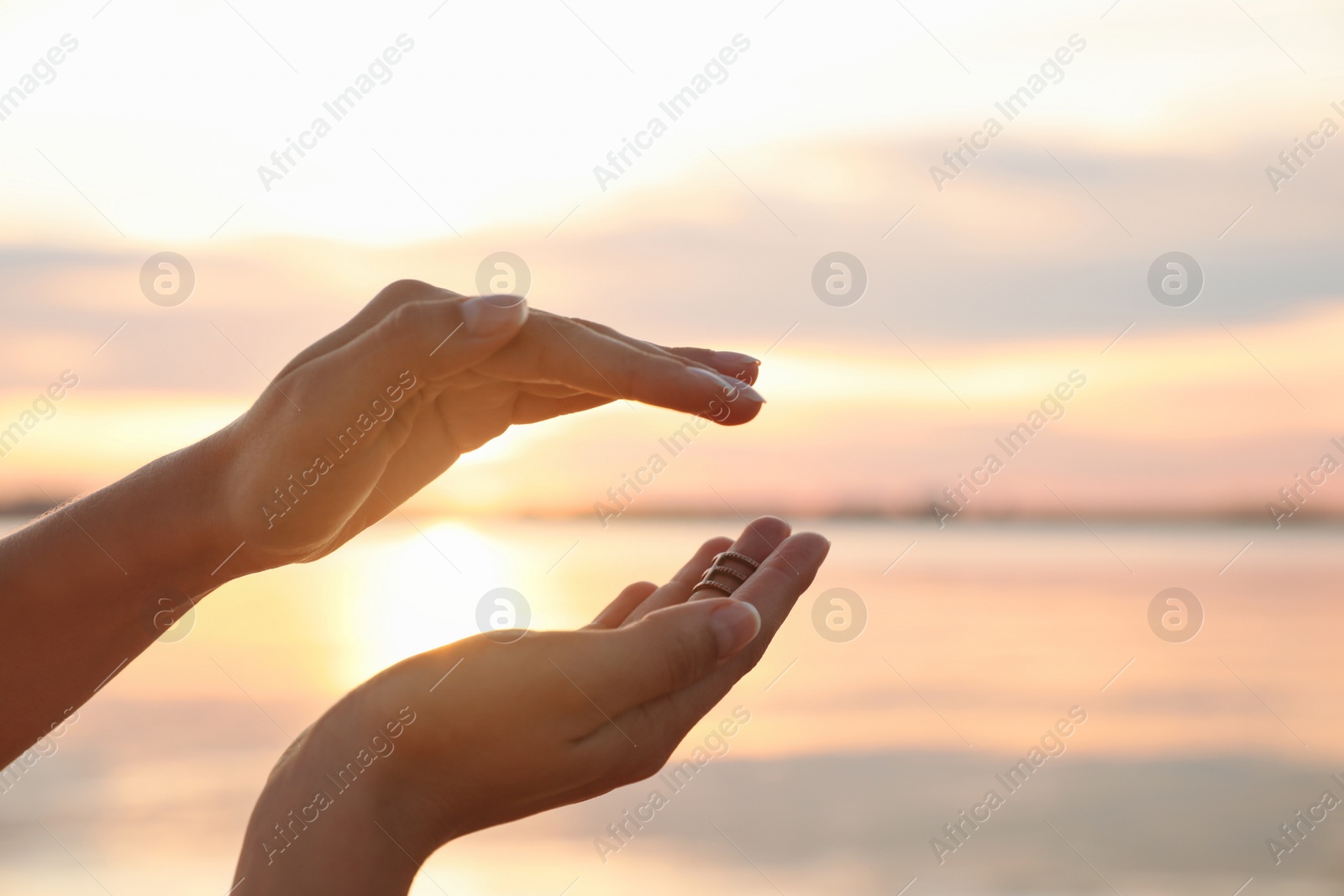 Photo of Young woman enjoying beautiful sunset near river, closeup. Nature healing power